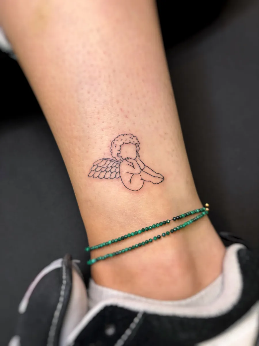 Kleiner Engel als Fineline Tattoo am Knöchel