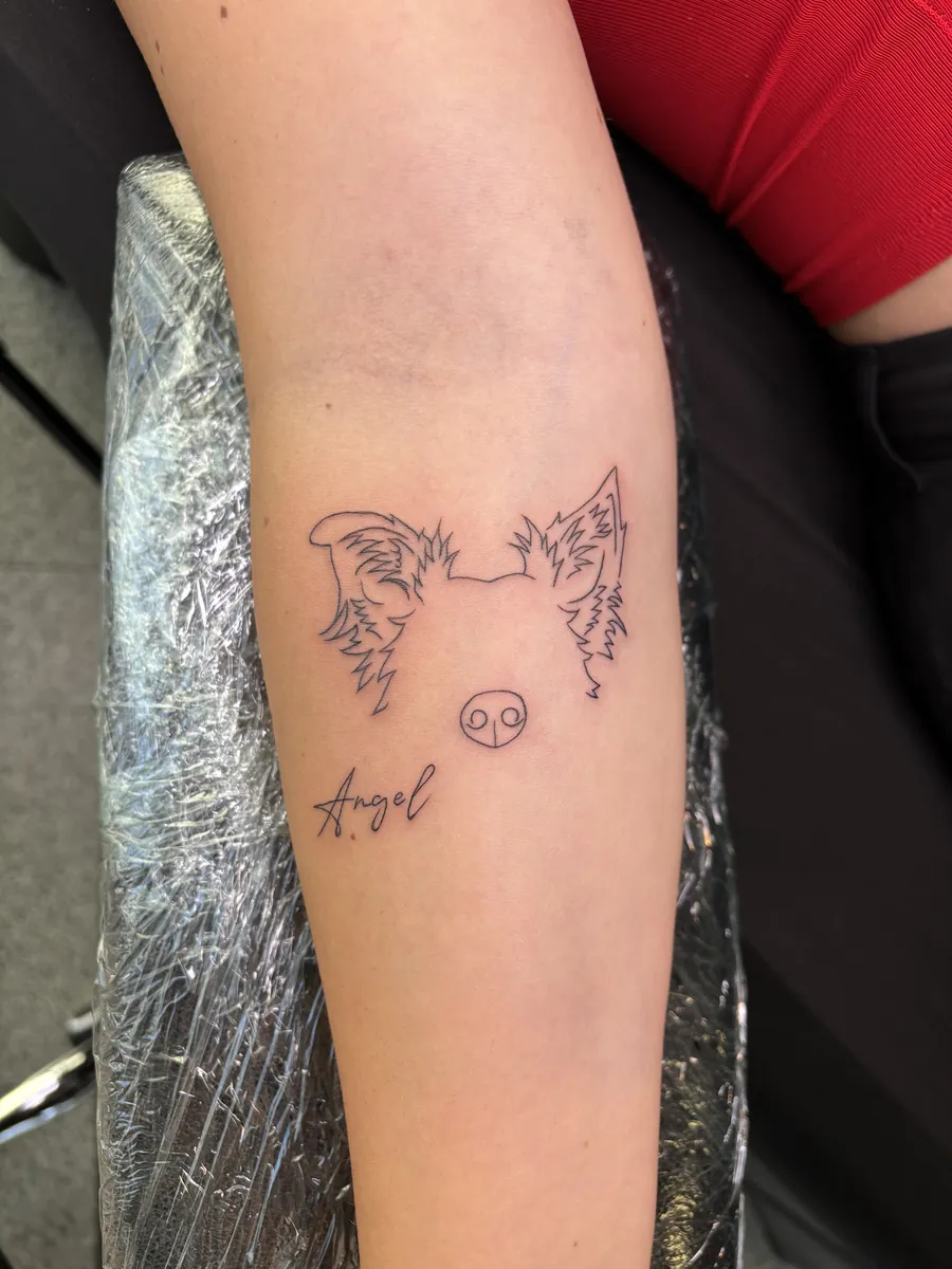 Zwei Hundeköpfe, Sternzeichen und Schriftzug als Fineline Tattoos am Unterarm